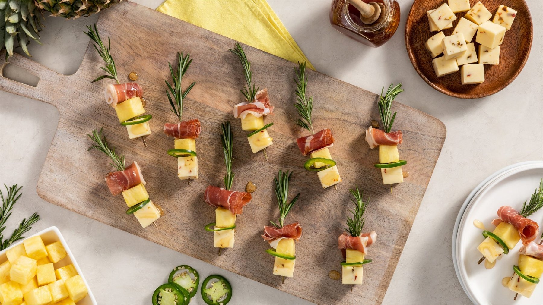 fresh rosemary sprigs skewered with pineapple, prosciutto, jalapeno, and pepper jack cheese and drizzled with honey