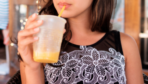 close up photo of a girl sipping a mango smoothie
